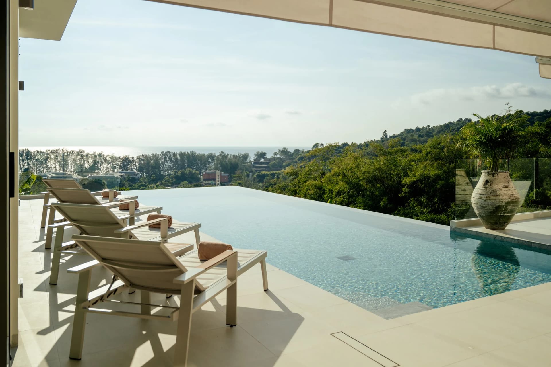 The pool of finished villa 15 spilling toward the green valley and the sea